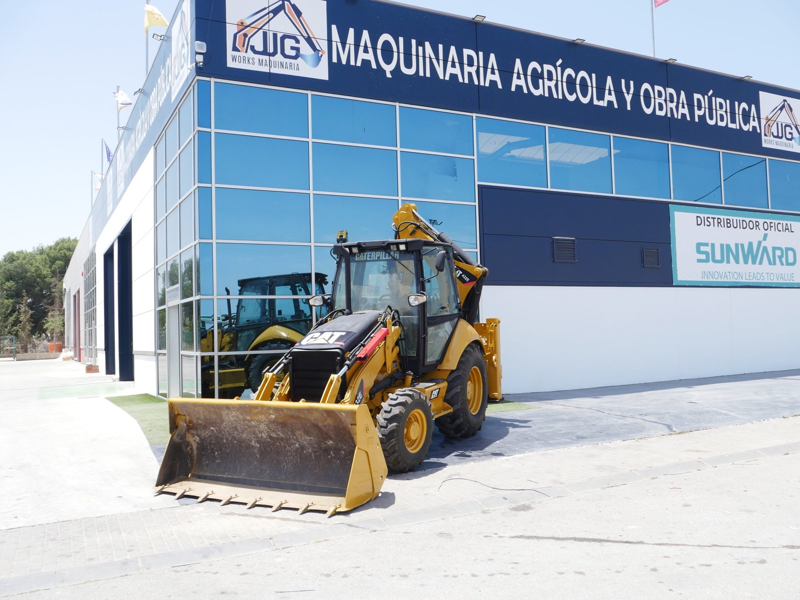 Retroexcavadora CAT 432E con almeja delantera, pinzas y mandos pilotados, ideal para construcción y obra pública