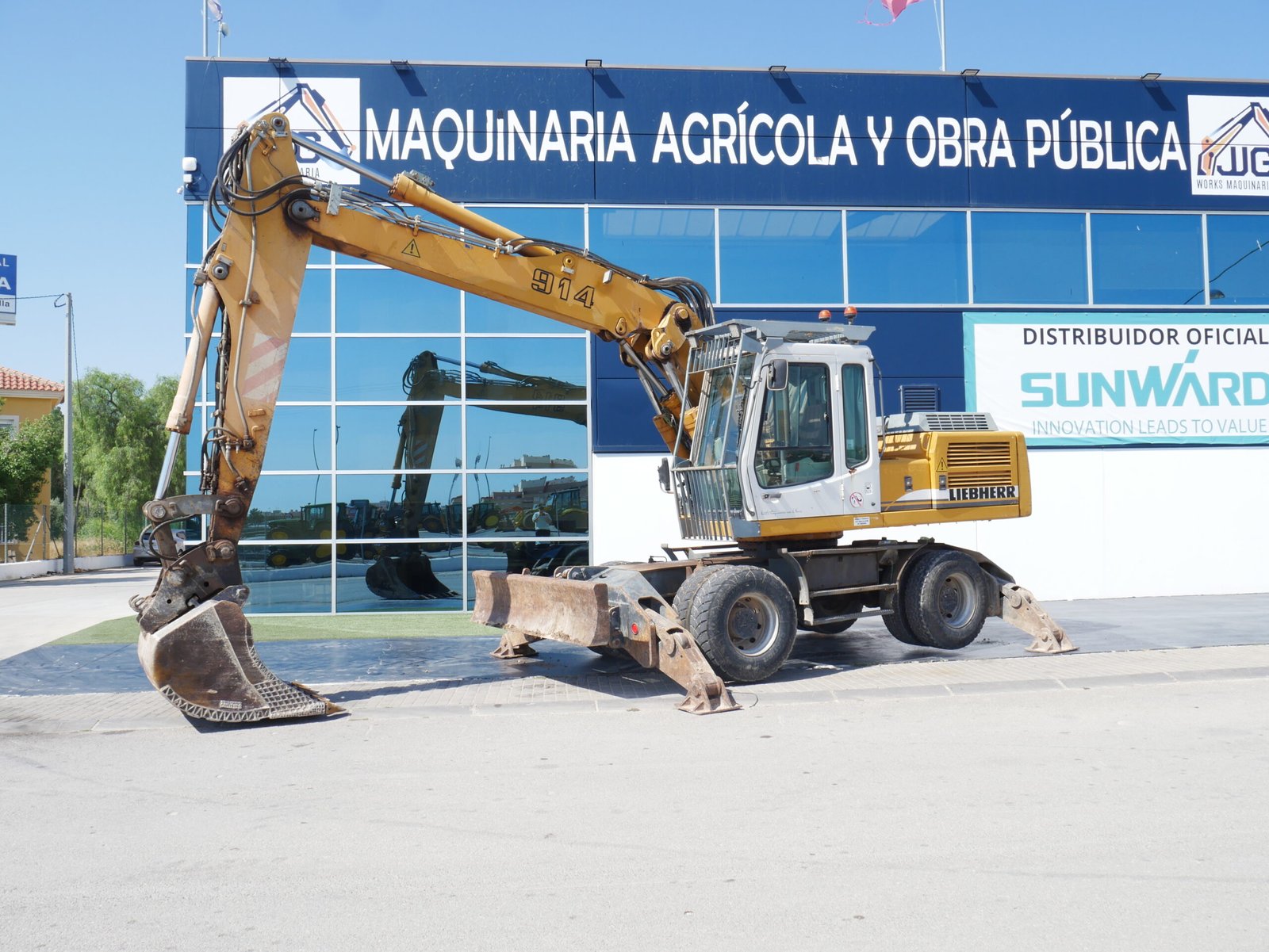 Excavadora de ruedas Liebherr A 914 B con hoja bulldozer, balancín largo y enganche rápido operando en obra urbana