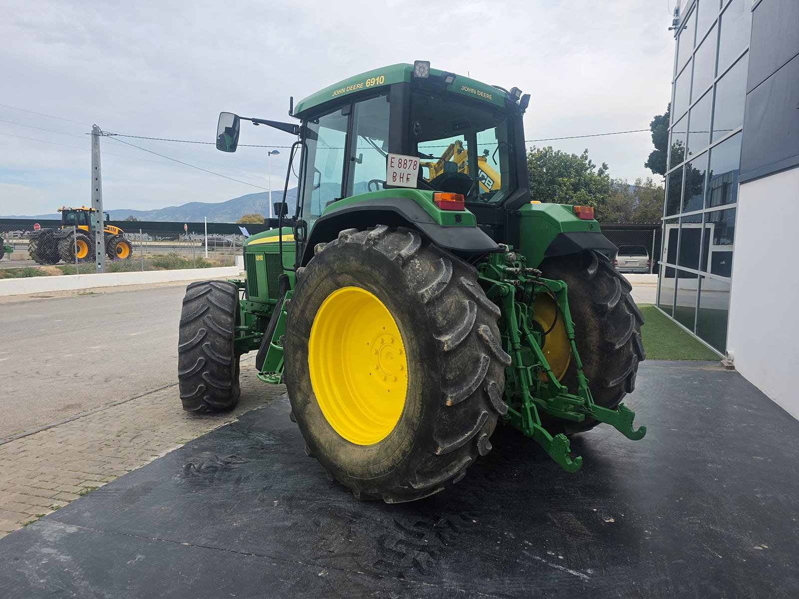 Tractor John Deere 6910 trabajando en campo Vista diagonal del John Deere 6910 Ruedas del tractor John Deere 6910
