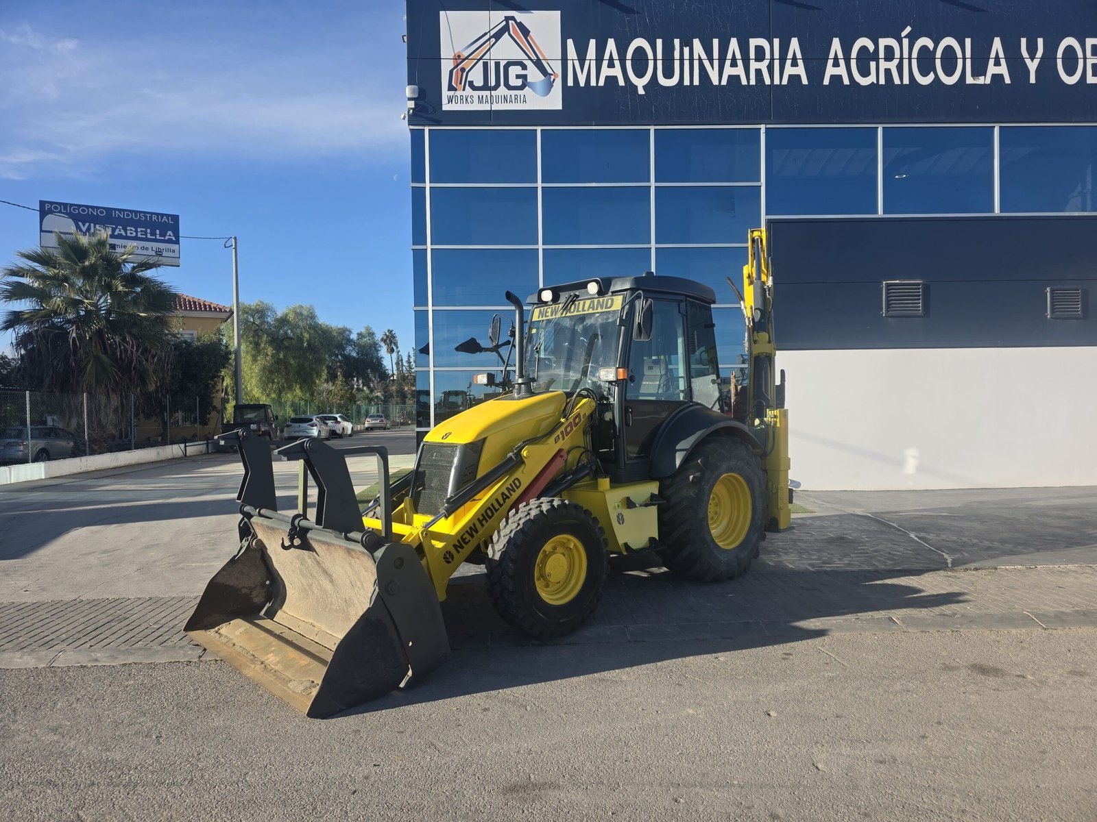 Parte trasera New Holland B100B con brazo excavador Cabina New Holland B100B interior mandos pilotados New Holland B100B con pinzas porta palets Retroexcavadora 4x4 New Holland B100B
